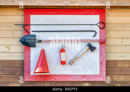 Wand- Feuer Schild mit Feuerwehr tools. Schaufel, Haken, ax, Kegel Schaufel, Feuerlöscher und andere Anlagen in Brand Punkt aufgehängt. Stockfoto