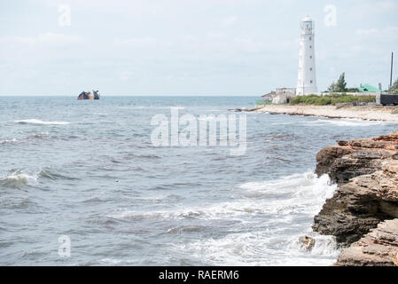 Landschaft von Wellen im Meer und ein Stück Küste mit Leuchtturm. Stockfoto