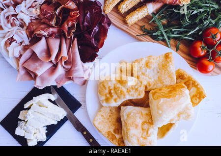 Traditionelle italienische Emilia Romagna, Bologna Region Vorspeise die Zubereitung von Pastasaucen fritte - gebratener Teig, Essen mit Gorgonzola Käse, verschiedene Fleisch- und Stockfoto