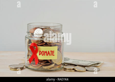 Geld Glas voll von Münzen mit rotem Band und Label Spenden - die AIDS-Hilfe und Forschung Fonds Konzept Stockfoto