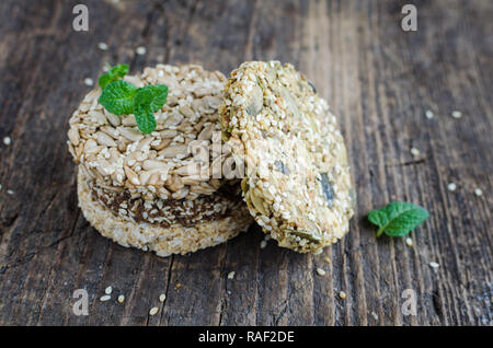 Dessert Müsli Snacks. Fitness diätetische Lebensmittel. Kozinaki mit Sesam, Erdnuss-, Sonnenblumen- und Kürbiskernen und Chocolate Chip auf alten rustikalen Holzbrett, Stockfoto