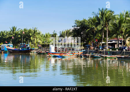 Traditionelle Boote auf dem Thu Bon Fluss gesäumt von Palmen in der Altstadt der historischen Stadt. Hoi An, Quang Nam, Vietnam, Asien Stockfoto