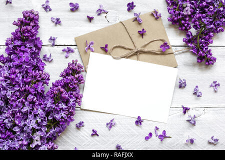 Stilvolle branding Mockup ihre Kunstwerke anzuzeigen. Grußkarte und lila Blüten mit weißem Holz- Hintergrund. Flach Top View Stockfoto