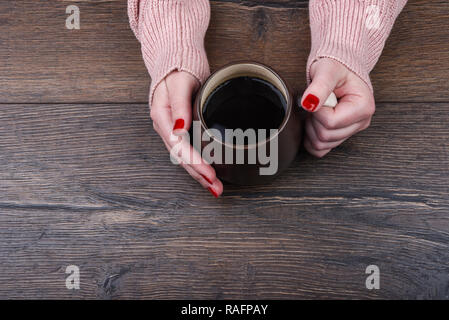 Das Mädchen hält den Griff eines großen Becher Kaffee Stockfoto