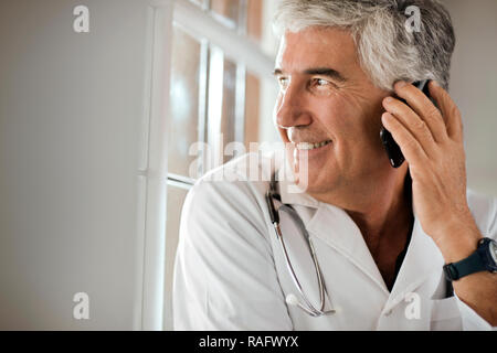 Portrait von männlicher Arzt über sein Mobiltelefon. Stockfoto