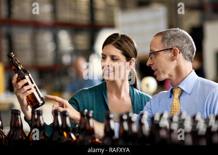 Zwei Kollegen mit der Prüfung einer Reihe von Bierflaschen. Stockfoto