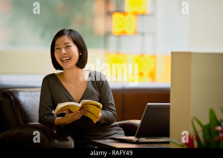 Frau sitzt auf einem Sofa in der Lobby ein Buch lesen. Stockfoto