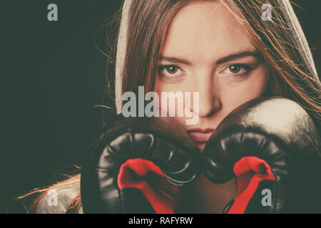 Bekämpfung von Boxen und Verteidigung. Sportlichkeit und starken Körper. Junge Frau tragen Sportswear und Boxhandschuhe Abdeckung Gesicht schauen Gegner. Stockfoto