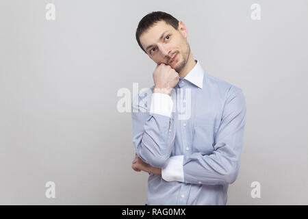 Nachdenklich stattlichen Borste Geschäftsmann in klassischem Hellblau Shirt mit verwirrt Gesicht und weg schauen und sein Kinn berühren. indoor Studio Stockfoto