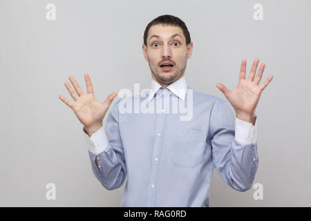 Portrait von schockiert stattlichen Borste Geschäftsmann in Classic blau Shirt stehend mit erhobenen Armen und Kamera mit Vernarbtem Gesicht. indoor Studi Stockfoto