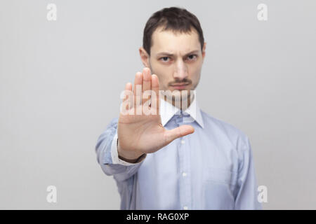 Porträt von Ernst stattlichen Borste Geschäftsmann in klassischem Hellblau Shirt stehen und zeigt stop Geste unterzeichnen. indoor Studio shot g isoliert Stockfoto