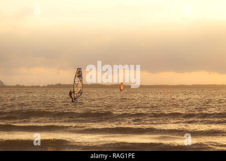 TALLINN, Estland - August, 10, 2017: Sportmen Windsurfer auf dem Meer gegen Sonnenuntergang orange sky Stockfoto