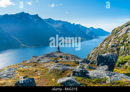 Mann stand auf der Klippe mit Blick auf schöne Ersfjorden Fjord an der Westküste der Insel Kvaloya in Tromsø Gemeinde in Troms County, noch Stockfoto