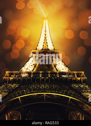 Nahaufnahme unter dem Eiffelturm bei Nacht, glänzend mit goldenen Lichter und Bokeh. Romantische Symbol für Verliebte in Paris, Frankreich. Stockfoto