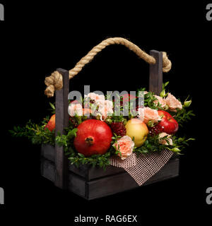 Erstaunlich genießbare Jahrestag Geschenk in Form von einer Holzkiste mit Rosen und verschiedene Früchte auf einem schwarzen Hintergrund gefüllt Stockfoto