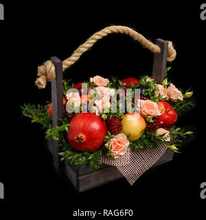 Originelles Geschenk in Form von einer Holzkiste mit Blumen und Früchte auf einem schwarzen Hintergrund gefüllt Stockfoto