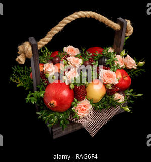Genießbare einzigartiges Geschenk für einen Urlaub in Form einer Holzbox mit Blumen und Früchte auf einem schwarzen Hintergrund gefüllt Stockfoto
