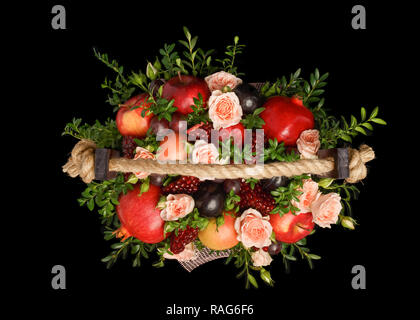 Genießbare einzigartiges Geschenk für einen Urlaub in Form einer Holzbox mit Blumen und Früchte auf einem schwarzen Hintergrund dargestellt. Ansicht von oben Stockfoto