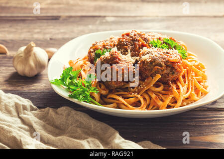 Linguine Nudeln mit Hackfleischbällchen in Tomatensauce und Petersilie auf rustikalen Holzmöbeln Hintergrund. Selektive konzentrieren. Stockfoto