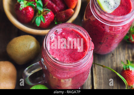 Smoothie mit Erdbeeren, Kiwi und Heidelbeeren in Töpfen auf rustikalen Holzmöbeln Hintergrund. Gesundes Frühstück. Stockfoto