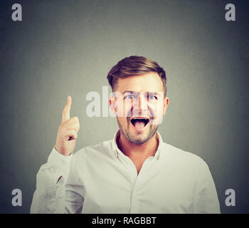 Aufgeregt glücklich Mann im weißen Hemd mit helle Idee nach oben auf grauem Hintergrund Stockfoto