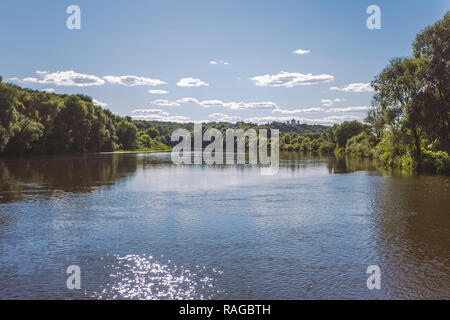 Schöne sonnige Landschaft Landschaft mit strahlend blauen Himmel, weiße und flauschige Wolken, grüne Bäume am Ufer und funkelnden glänzende Wasseroberfläche. Horizont Stockfoto