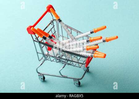 Insulinspritzen in Rot Warenkorb Trolley auf blauem Hintergrund Stockfoto