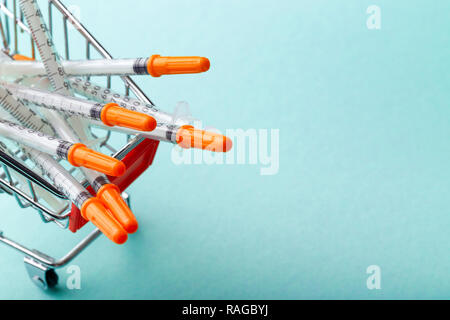 Insulinspritzen in Rot Warenkorb Trolley auf blauem Hintergrund Stockfoto
