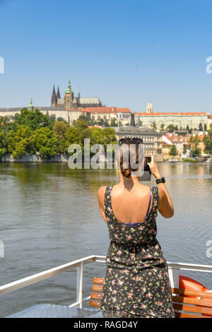 Prag, tschechische Republik - Juli 2018: Person, die Bilder von einer Schifffahrt auf der Moldau in Prag. Im Hintergrund ist St. Vitas Kathedrale Stockfoto