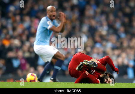 Von Manchester City Vincent Kompany reagiert, nachdem ein Angriff auf Liverpools Mohamed Salah (rechts), aus der sich eine gelbe Karte, während der Premier League Match an der Etihad Stadium, Manchester. Stockfoto