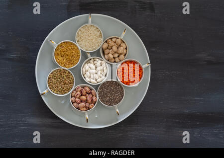 Vegan protein Quelle. Hülsenfrüchte - Linsen, Kichererbsen, Bohnen, interne Hülsen, Bulgur, Chia Samen auf schwarzem Hintergrund. Ansicht von oben kopieren. Stockfoto