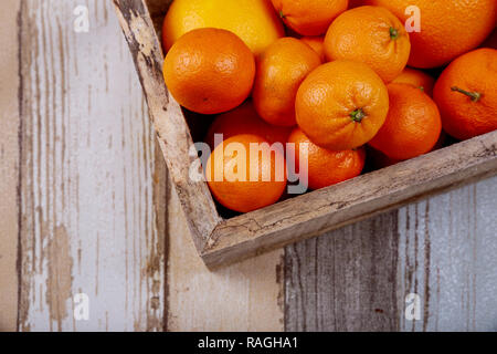 Frische Orangen und Mandarinen in einer alten Holzkiste. Auf einer hölzernen Hintergrund. Stockfoto