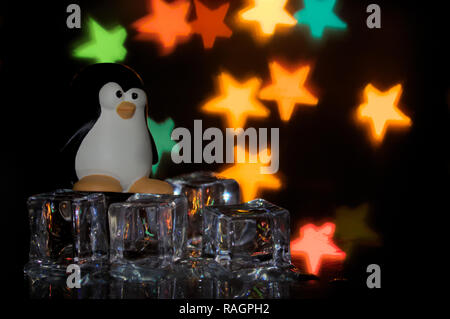 Der pinguin Emblem der freien Software, Tux, auf Eiswürfel mit bunten Sterne im Hintergrund Stockfoto