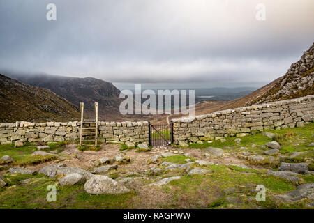 Das ist ein Bild von der Mauer aus Stein und Tor, das an der Spitze der Hasen Lücke in der Mourne Mountains in Nordirland Stockfoto