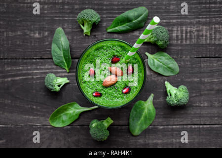 Grün gesund Smoothie in ein Glas mit Brokkoli, Spinat, Mandeln, Granatäpfel und Chia Samen mit einem Stroh über rustikalen Holztisch. top View Stockfoto