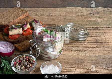 Rollmops mit Salz, Pfeffer, Kräuter und Zwiebel in ein Glas mit Sandwiches zum Frühstück. Nach oben Schließen Stockfoto