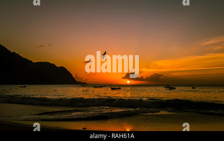 Sonnenuntergang über dem kleinen, abgelegenen Dorf von Castara auf der wunderschönen Insel Tobago in der Karibik mit Seevögeln und Fischerbooten. Landschaft Stockfoto