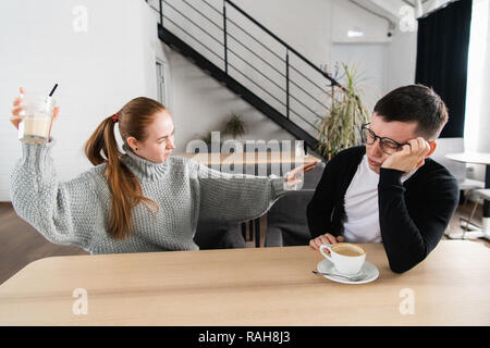 Paar Kämpfe in den Morgen. Frau wirft ein Glas zu ihrem Mann. Beziehung Probleme Stockfoto