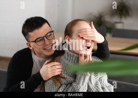 Lassen sie sich überraschen Schöne romantische Paare im Cafe. Der Mensch ist in den Augen seiner Freundin, während Sie für eine Überraschung wartet Stockfoto