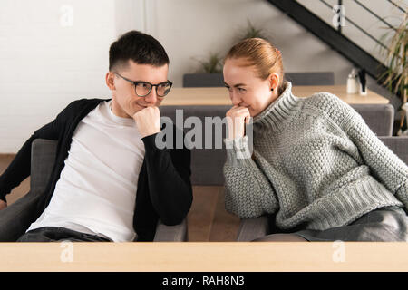 Freunde mit verschwörerischen Blick sitzen vor der jeweils anderen und machen einen Plan Stockfoto