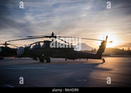 Ein U.S. Army AH-64 E Apache Hubschrauber 16 Combat Aviation Brigade zugeordnet, 7 Infanterie Division sitzt für die Ausbildung am Joint Base Lewis-McChord, Wash., Feb 2, 2017 bereit. Der klare Himmel erlaubt Mount Rainier zum Erstellen einer schönen Kulisse als die Sonne aufging. Stockfoto