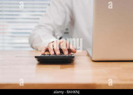 Asiatische Geschäftsmann oder Buchhalter Arbeiten zeigen graph Diskussion und Analyse Daten Diagramme und Grafiken und mit einem Taschenrechner zahlen zu berechnen. Busi Stockfoto