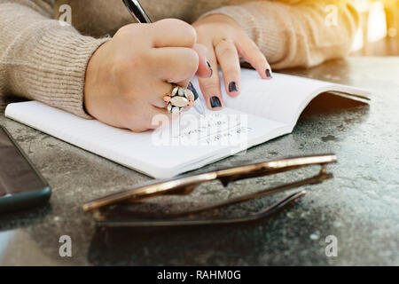 Blick auf weibliche Hände schreiben ihr Leben Ziele in einer Zeitschrift Stockfoto
