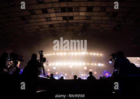 Fernsehen von einem Kameramann bei einem Konzert. Kamera mit dem Operator ist auf der Plattform. Silhouetten auf dem Hintergrund der bunte Strahl Stockfoto