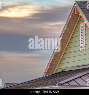 Weihnachtsbeleuchtung auf den Rand des Daches eines Hauses im Morgengrauen Utah. Die Leuchten sind in verschiedenen Farben und das Haus ist grün und kann mit dem Himmel gesehen werden. Stockfoto