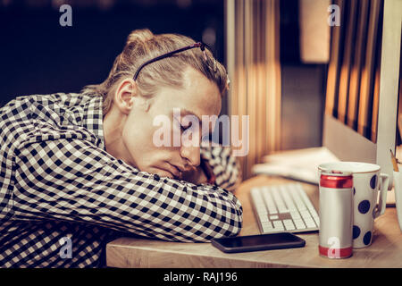 Müde junge Mann lag auf seinem Arbeitsplatz Stockfoto