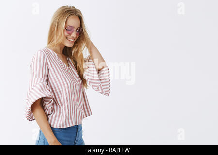 Gefühl wie Mode Modell auf Französisch Podium. Portrait von stilvollen und gut versichert - Suche blonde europäische Frau, Sonnenbrille und gestreifte Bluse, berühren, Haar, lächeln und nach unten schauen. Stockfoto