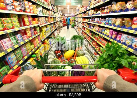 Volle Einkaufswagen den Gang hinunter geschoben, Food Hall, Supermarkt Stockfoto