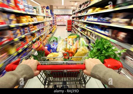 Volle Einkaufswagen den Gang hinunter geschoben, Food Hall, Supermarkt Stockfoto