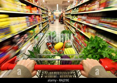 Volle Einkaufswagen den Gang hinunter geschoben, Food Hall, Supermarkt Stockfoto